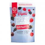 A clear plastic jar with a white screw lid displays bright orange-red gummy fruits through the transparent body. The label shows 'Vegums Gut Health Wholefruit' in bold green, fruit illustrations, nutritional icons, and 'Vegums Lifestyle' on a clean white backdrop. Soft studio light adds subtle gloss.