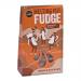 A glossy gift pack of chocolate orange fudge sits open, revealing square, marbled pieces dusted with cocoa. The box shows bright orange and brown branding and a clear window. Soft, dense slices display swirls of chocolate and citrus-colored streaks. A gold ribbon ties the pack adding a subtle sheen.