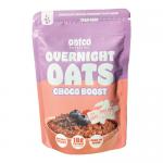 A rectangular carton and scattered single-serve pouches show the Oatco logo on warm brown and cream backgrounds. Chocolate swirls, cocoa nib illustrations and whole oat imagery decorate the front. Panels of small text and icons line the sides.