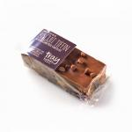 The photo shows twelve rectangular biscuit tiffin traybakes arranged in a bakery tray. Each square displays a glossy milk chocolate topping over a dense, crumbly biscuit filling with visible biscuit pieces, chocolate swirls and clean-cut edges on a rustic board.