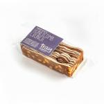 Twelve golden rectangular traybakes sit neatly in a tray, each showing a soft sponge base, a creamy honey-colored topping, scattered honeycomb toffee pieces and crushed biscuit, with a sticky caramel drizzle and crumbly edges.