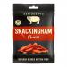 A close-up of individually wrapped chorizo sticks branded Serious Pig, each 35g cylinder shows deep red, marbled meat with paprika specks. Clear film and a brown label with pig logo and white text sit on a wooden board, some sticks whole and some thinly sliced. Warm soft lighting reveals oily sheen.