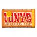 A bright, graphic wrapper shows a bold Tony's Chocolonely logo across the center with off-kilter, chunky bar segments illustrated beneath. Vivid colors and hand-drawn lines frame a milk chocolate bar broken to reveal gooey caramel and scattered sea salt crystals.
