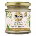 Clear glass jar displays pale, creamy tahini with a smooth, slightly glossy surface. A white paper label encircles the jar, featuring a green Biona logo and minimalist black and brown lettering stating Organic Tahini White No Salt Not Roasted 170g. A silver lid tops the jar.