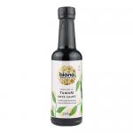 A clear glass bottle of Biona Organic Tamari Sauce stands upright, containing dark mahogany liquid. The label uses green and cream panels with the Biona logo, 'Tamari' and 'Wheat Free' wording. A black screw cap seals the neck against a bright white backdrop. Light glints on the bottle's curved glass.