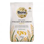 A clear plastic pouch of Biona Organic white macaroni stands upright, revealing pale, bronze-extruded elbow pasta. A green-and-white label displays the Biona logo and product name, weight text, and simple graphics against a clean, neutral background. Soft light shows ridged texture and sealed seams.