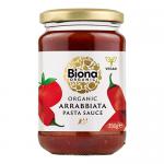 Photo shows a clear glass jar of Biona Organic Arrabbiata Hot & Spicy pasta sauce. Deep red, slightly textured sauce fills the jar. The white label bears green and red branding, product name and ingredient text. A metal lid seals the top. It sits on a neutral surface, softly lit, with chilli flecks.
