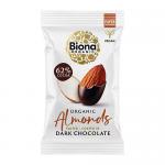 An open pouch and several small packets of Biona Organic Dark Chocolate Roasted Almonds sit on a pale wooden surface. Glossy, dark chocolate-coated almonds spill out beside scattered whole nuts. Packaging features the Biona logo, organic wording and earthy green and cream tones. Soft natural glow!!!