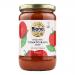 Six 680g tins of Biona Organic Tomato Basil Soup sit together on a pale surface. Vivid red labels show juicy tomato artwork and sprigs of basil around the bold Biona logo and organic marks. Shiny metal lids and subtle shadows add depth to the composition. Light reflects faintly on the label edges...