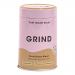 Shiny cylindrical tin labeled Grind Coffee Roasters sits upright on a neutral surface. A matte black lid tops the compact 90g container; minimalist logo and bold white type contrast with a deep brown band. Soft studio light highlights metallic texture and casts a subtle shadow. Background is softly.