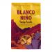 Bright red and yellow bag of Blanco Niño Meaty Asado tortilla chips sits upright, showing a bold logo and sizzling grilled meat imagery. Crisp triangular chips peek from a transparent window, while seasoning flecks and texture detail highlight crunchy, savory surfaces. Glossy finish subtly reflects.