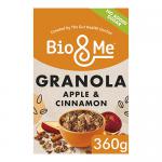 A resealable pouch of Bio&Me Apple + Cinnamon Gut-Loving Granola sits beside a bowl of golden clusters, scattered oats and dried apple pieces. Cinnamon sticks and fresh apple slices frame the scene on a wooden surface, with soft natural light highlighting crunchy textures and a linen napkin nearby.