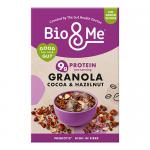A 360g Bio&Me Cocoa & Hazelnut granola pack stands upright on a plain background. The brown-and-cream packaging shows the Bio&Me logo, photos of hazelnuts, cocoa chunks and oat clusters, with scattered seeds and a spoonful of granola in the foreground.