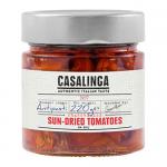Glass jar holds chargrilled sundried tomatoes packed in golden oil. Deep crimson tomato halves show charred edges and wrinkled texture; flecks of herbs and sliced garlic float among glossy pieces. The jar carries a rustic label with the Casalinga name and simple graphic Soft oil sheen catches light