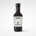 A single glass bottle of Casalinga balsamic vinegar stands upright, filled with dark mahogany liquid. It has a slender neck, a black screw cap and a cream label with red trim, scripted brand name and subtle gold accents. Light glints off the smooth curved glass surface. Shelf backdrop with soft blur.