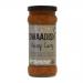 Six glass jars of Swaadish Kalonji Curry Sauce line up against a pale background. The vivid orange curry fills each jar, while bright labels display the Swaadish logo, a kalonji seed illustration, ingredient highlights and product name. Black screw tops finish the set. Metallic foil accents shimmer.