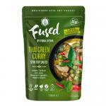 A glossy jar of bright emerald-green Thai curry paste sits open on a wooden board, flecked with chili seeds and kaffir lime rind. Fresh basil and sliced red chili scatter nearby. Light catches the oily sheen; textures range from smooth purée to coarse herb fragments. A small wooden spoon sits nearby