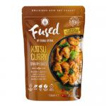 Glossy golden katsu pieces sit atop a vibrant stir-fry of orange curry sauce, charred bell peppers, broccoli florets and julienned carrots. Sesame seeds and sliced scallions scatter across the glossy surface, steam rising from a shallow bowl on a rustic wooden table.