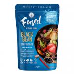 A squat glass jar with a matte black screw cap contains glossy, dark-brown stir-fry sauce. A cream wraparound label features Fused by Fiona Uyema in flowing script, Black Bean Stir Fry Sauce 125g in bold type, subtle soy-bean graphics and minimal nutritional icons.