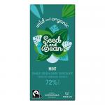 A wrapped Seed & Bean extra-dark chocolate bar sits on a neutral background. The packaging displays 72% extra dark and mint with small mint-leaf artwork and illustrations of seeds. A torn corner reveals a dark, glossy chocolate slab flecked with tiny seeds. A thin silver foil peeks from the wrapper.