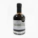 Several glass bottles of Wild Island dressings stand on a rustic wooden board, one open and showing deep fig-balsamic glaze. Fresh figs, scattered spice seeds and sprigs of herbs surround a small spoon of glossy dressing. Soft natural light and a blurred background highlight textures. Rich mahogany.