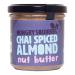 Six glass jars of Hungry Squirrel Chai Spiced Almond spreads sit arranged in two rows inside a kraft carton; each jar shows a cream-colored lid, a warm cinnamon-brown spread visible through glass, and a beige label with subtle chai spice illustrations and clear branding, nearby a wooden spoon rests.