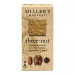 Image shows a neatly arranged stack of thin golden-brown wafers with visible hazelnut, almond and walnut pieces, beside a rustic kraft-paper packet labeled Miller’s Harvest. Soft natural light highlights the crunchy texture and scattered nut fragments on a wooden surface.