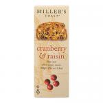 Golden-brown rectangular toast biscuits lie stacked with several loose pieces nearby; each slice shows scattered ruby cranberries and dark raisins embedded in a grainy, crumbly texture. A light dusting of sugar, warm tones and soft shadowing evoke a rustic bakery scene. Soft highlights rim the fruit