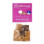 A clear plastic grab bag shows 16 assorted buttermilk confections, each in colorful, glossy wrappers. The 175g label sits on a bright branded sticker. Candies vary in shape and pale cream tones, scattered against a neutral background.