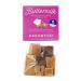 A clear plastic grab bag shows 16 assorted buttermilk confections, each in colorful, glossy wrappers. The 175g label sits on a bright branded sticker. Candies vary in shape and pale cream tones, scattered against a neutral background.