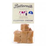 Image shows a grab bag of clotted cream buttermilk confections: a 175g packet labeled as 16 pieces. Individually wrapped pale cream sweets nest in translucent cellophane inside a soft pastel package, with simple typography and a subtle buttery sheen on the candies. Close-up shows light reflections..