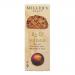 A neat stack of six round artisan toasts sits on a rustic wooden board. Each golden-brown biscuit has a crackled surface studded with fig slices and glossy sultanas. An open carton with muted, earthy packaging sits beside them, with soft natural lighting and simple styling.