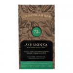A matte black wrapper of Chocolarder Ashaninka 70% Dark sits centered on a neutral background. Gold lettering and a simple indigenous-inspired emblem contrast with deep-brown chocolate squares peeking from an open edge, scattering a few cocoa nibs nearby. Warm highlights accent gentle ridges nearby.