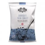 A photo shows a box of slim pale-blue snack packets labeled Made For Drink English Heritage Dorset Sea Salt. Each 40g bag sits upright in neat rows, packet fronts showing coastal illustrations, scattered salt flakes and crisp imagery, forming a 24-pack display Soft coastal hues and clean typography
