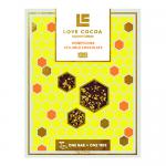 A set of twelve 70g Love Cocoa bars sits in a neat grid, each wrapper showing warm honey-gold accents and honeycomb imagery. The Milk chocolate bar with honeycomb is visible on one open pack, revealing textured chocolate studded with crisp golden honeycomb pieces. Matte finish with small brand logo.