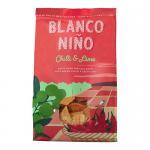 A bright green and red packet of Blanco Niño Chilli & Lime tortilla chips stands upright against a neutral background. The logo tops a vivid chilli-and-lime illustration; a clear window reveals triangular, lightly speckled chips and printed nutrition text along the base.