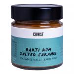 Six upright 210g bottles of CRWST Barti Rum Salted Caramel sauce stand in two neat rows on a neutral background. Glossy amber caramel shows through clear bottles. Cream labels display the brand and a caramel-drip motif; silver caps catch soft light.