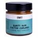 Six upright 210g bottles of CRWST Barti Rum Salted Caramel sauce stand in two neat rows on a neutral background. Glossy amber caramel shows through clear bottles. Cream labels display the brand and a caramel-drip motif; silver caps catch soft light.