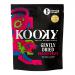 Bright magenta, gently dried dragon fruit slices show speckled black seeds and translucent edges, slightly curled and glossy with a wrinkled texture. Several pieces rest beside small colorful Kooky packets on a clean white background.