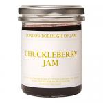 A photo shows six glass jars of London Borough of Jam Chuckleberry Jam, each 220g, arranged in a neat pack. Deep purple jam fills clear jars with white lids and cream labels bearing a playful logo, berry illustration and simple black typography on a neutral background. Soft studio lighting highlights.