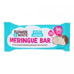 A rectangular meringue bar displays crisp, ivory peaks and a marbled white-and-caramel surface. Delicate edible flower petals scatter across the top. A glossy salted-caramel drizzle threads between airy ridges, while fine salt crystals and crumbly meringue fragments catch the light. Soft amber glow.