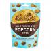 Close-up image shows a small paper bag branded with Joe & Seph’s logo spilling glossy milk chocolate popcorn bites onto a wooden surface. The popcorn clusters glisten, with light reflecting off smooth chocolate; background is softly blurred, keeping focus on the textured treats. Soft warm lighting!!