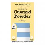Photo shows a multi-pack of twelve 100g Just Wholefoods vanilla custard powder units in a neat rectangular arrangement. Pale yellow and cream labels feature the Just Wholefoods logo, 'Vanilla Custard' wording and a vanilla pod illustration, with nutrition text and barcodes visible. Soft low shadows.