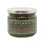 Six clear glass jars of Dylan's Pickled Samphire sit in two neat rows, each 250g jar showing bright green samphire strands suspended in pale brine. White labels with green and black text read Dylan's Chutney & Condiments; metal lids reflect soft studio lighting. Against a plain white backdrop. Soft.