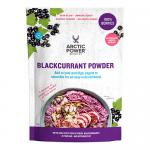 An arranged set of six Arctic Power Berries Blackcurrant Powder 70g packs sits on a light backdrop. Deep purple powder spills from an open jar beside ripe blackcurrants and green leaves. Clean, bright packaging displays bold typography and berry imagery. Soft shadows fall; a small wooden spoon sits.