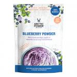 Six upright 70g blue sachets of Arctic Power Berries blueberry powder line a minimalist surface; bold logo and berry imagery face forward. A small glass jar reveals deep indigo powder beside fresh blueberries and a wooden scoop, all arranged in bright, airy lighting. Subtle frosted accents and white.