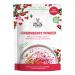 Six red-and-white sachets of Arctic Power Berries Lingonberry Powder sit on a light wooden table; one sachet is open, spilling fine, deep-red powder beside fresh lingonberries and green leaves under soft, natural light.