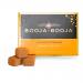 A compact box of eight glossy chocolate truffles nests in a clear tray beside a matte orange-and-brown sleeve. The sleeve shows orange slices and elegant script, while individual round truffles display glossy finishes and fine textured dusting under soft studio lighting. Soft highlights trace curves