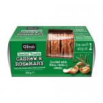 Brightly branded box sits against a neutral background; a clear window reveals thin, golden-brown seeded toasts flecked with cashew pieces and rosemary leaves. Several crisp rectangular slices stand fanned beside the box, showcasing rough edges, visible seeds and a rustic, crunchy texture. In frame.