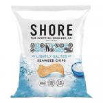A matte seafoam-green packet sits against a pale background, its logo and minimalist waves printed in white. Crisp, irregular dark-green seaweed chips spill from the torn top, showing speckled salt crystals and a light, brittle texture that catches soft studio light. Subtle shadowing defines textures